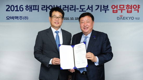 지난 18일 서울 강남 오비맥주 본사에서 오비맥주 정책홍보담당 장유택 전무(왼쪽)와 대교 사회공헌실 서명원 실장이 ‘2016 해피 라이브러리-도서 기부’ 업무협약(MOU)을 체결한 후 기념촬영을 하고 있다. (사진=오비맥주)