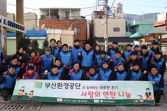 부산환경공단 관계자들이 12일 동구 범일동 일대에서 소외계층 연탄지원 봉사활동을 펼치고 기념사진을 찍고 있다. (사진제공=부산환경공단)