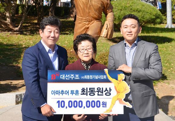 (사)최동원기념사업회 박재호 이사장(맨 왼쪽)과 고 최동원 선수의 어머니(가운데), 그리고 대선주조㈜ 조우현 대표이사(맨 오른쪽)가 최동원상 앞에서 기념촬영을 하고 있다. (사진제공=대선주조)